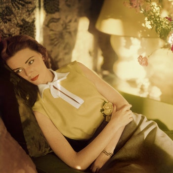 Model wearing a gold Irish linen sleeveless blouse buttoned in the back by Sidney Heller.