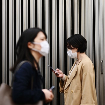 TOPSHOT  People wearing face masks amid concerns of the COVID19 coronavirus walk on a street in Tokyo's Yurakucho area...