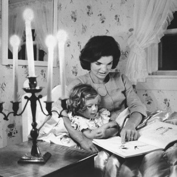 Jackie Kennedy wife of Senator reading book to her daughter Caroline in her bedroom at the family's summer home.