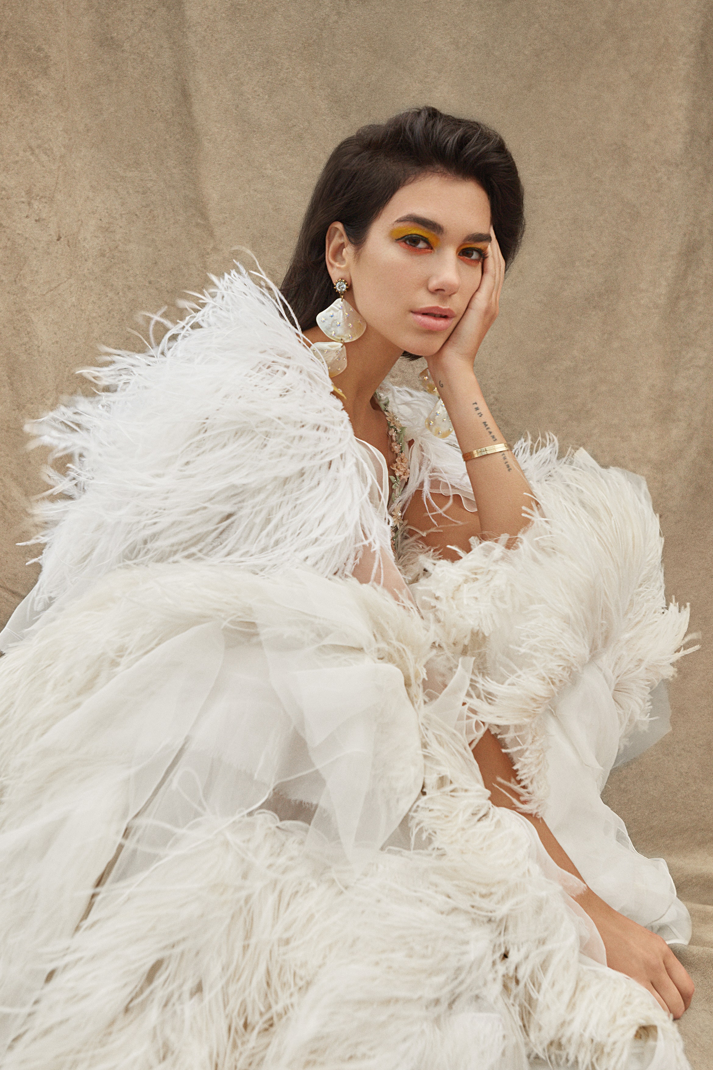 Youth Quake new generation of talents. Outdoor portrait of Dua Lipa wearing a cream dress feathers oversized shell drop...