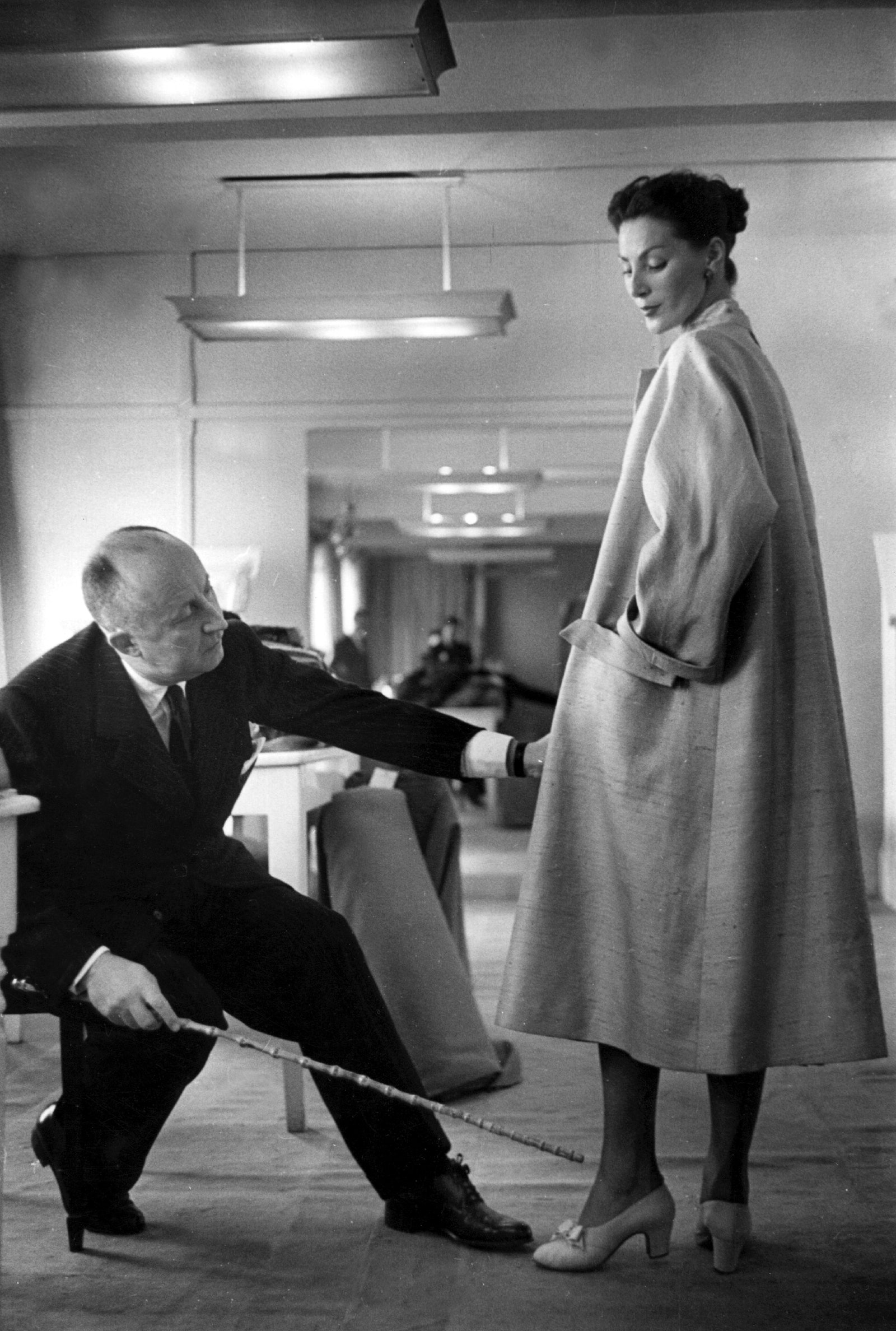 Кристиан Диор вносит поправки в пальто в парижской студии около 1952