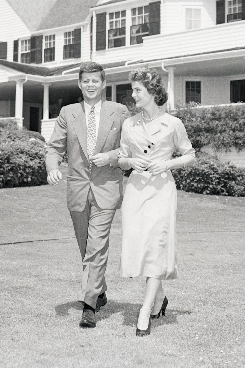 Senator John F. Kennedy and Miss Jacqueline Bouvier stroll across the lawn of his family's home after announcing their...