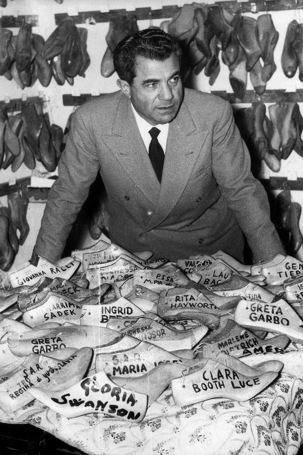 Italian fashion designer Salvatore Ferragamo in his shoe manufacturing in front of various celebrities' shoe forms....