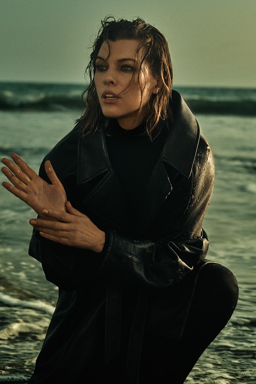 Actress Milla Jovovich wearing black leather trench coat viscose fabric trousers and black polo neck cashmere fabric...