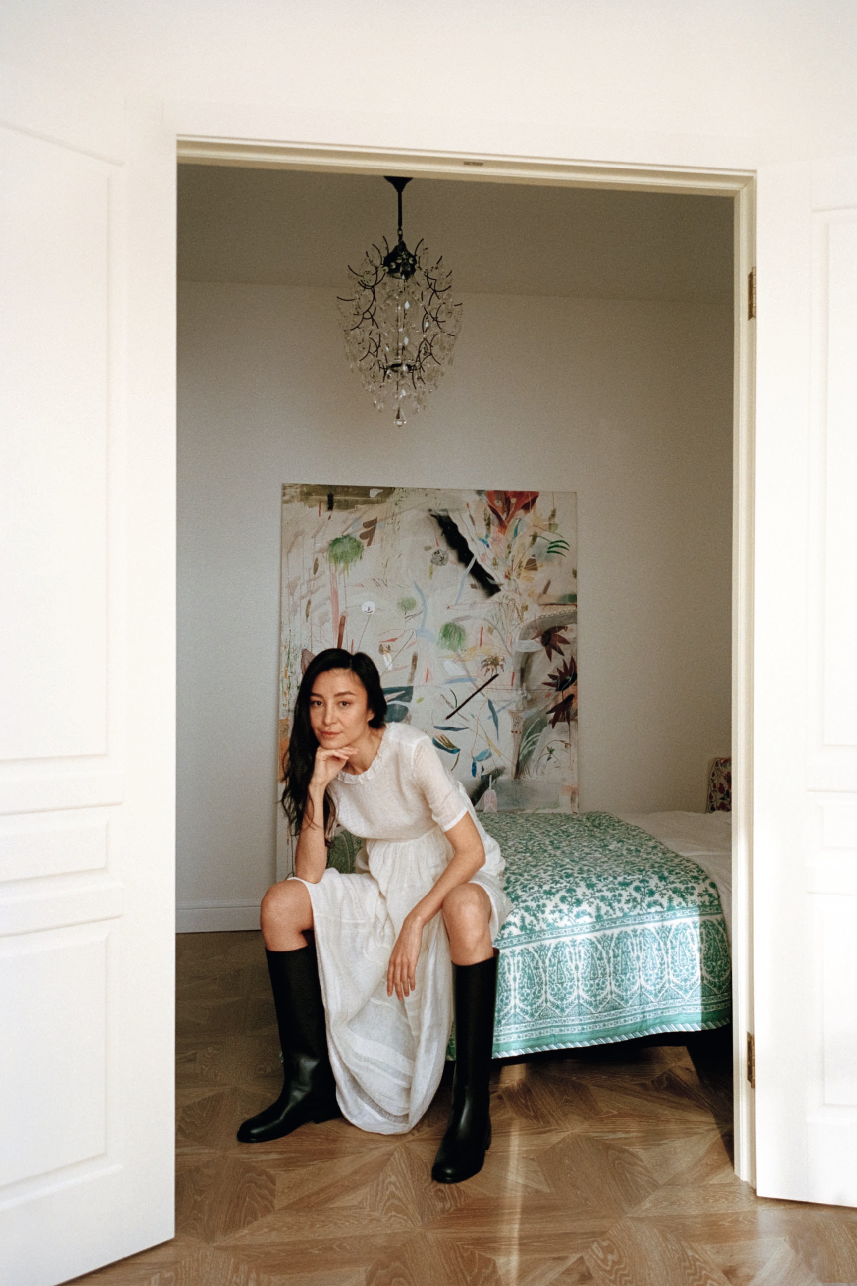 Fashion designer Aziza Azim wearing white cotton fabric short sleeved ruffled dress and black calf height leather boots...
