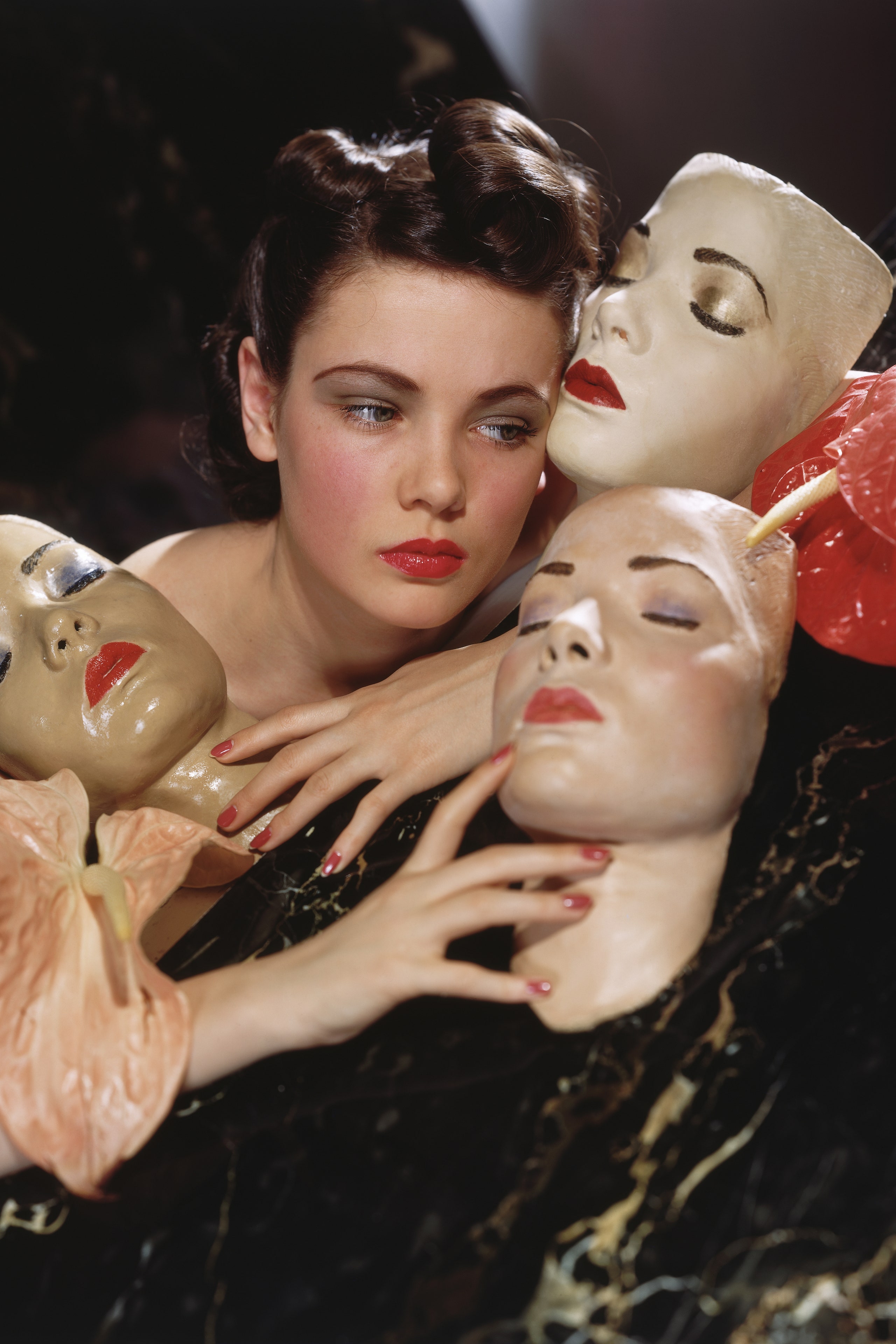Actress Gene Tierney posed with three portrait masks made by Lillian Bettinger and two anthurium flowers.    Local...