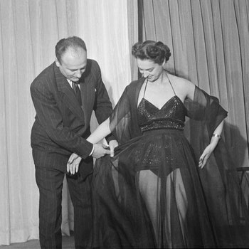Parisian designer Pierre Balmain is here with a model wearing his Midnight Bathing Suit with skirt.