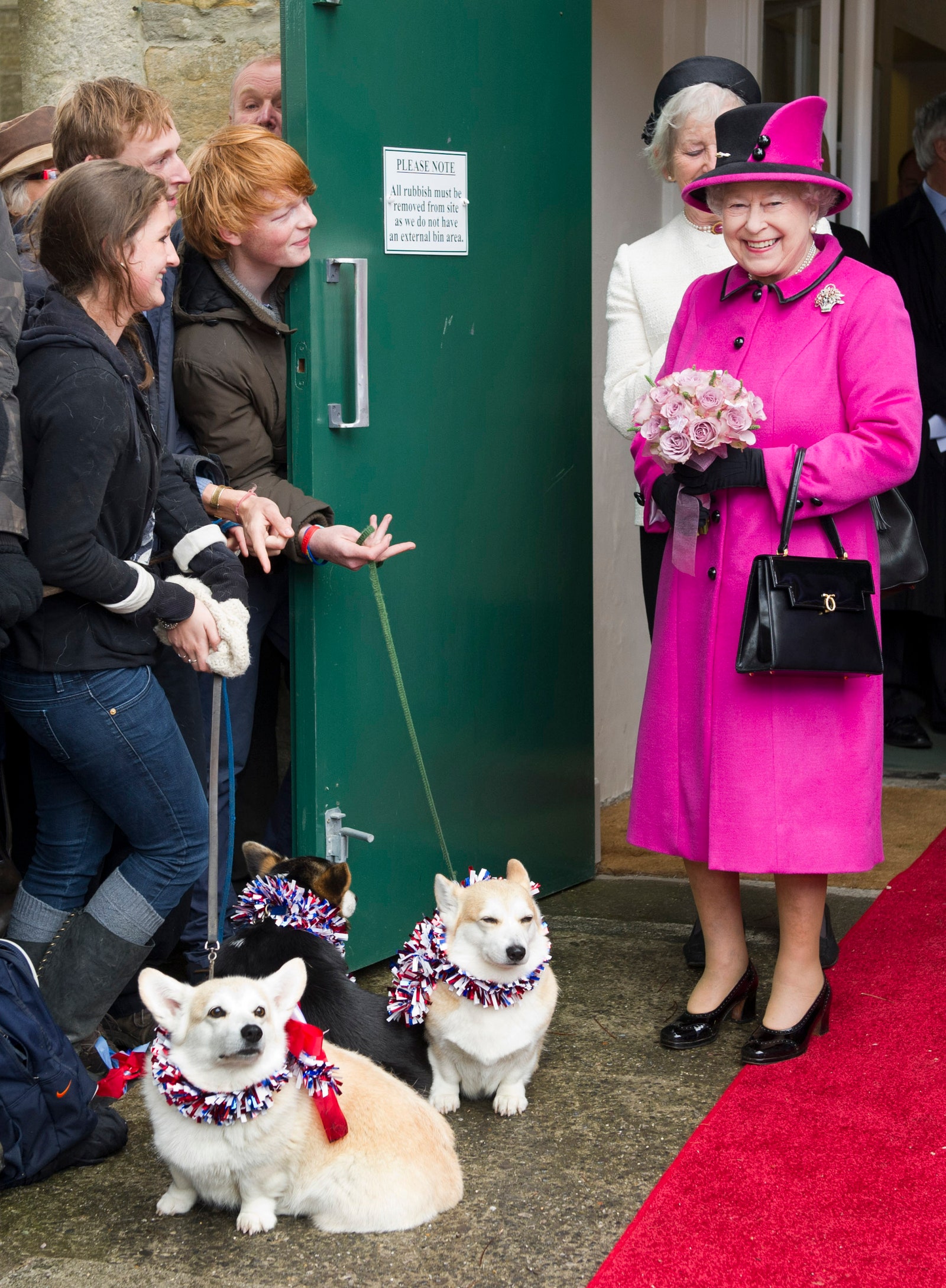 Image may contain Human Person Clothing Apparel Hat Animal Pet Canine Dog Mammal Pants and Elizabeth II