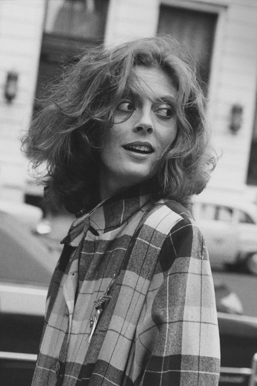 American actress Susan Sarandon wearing a plaid coat looking over her left shoulder hair blowing in her face Ms....