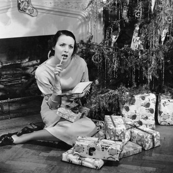 UNITED STATES  CIRCA 1950s  Woman under Christmas tree making list.