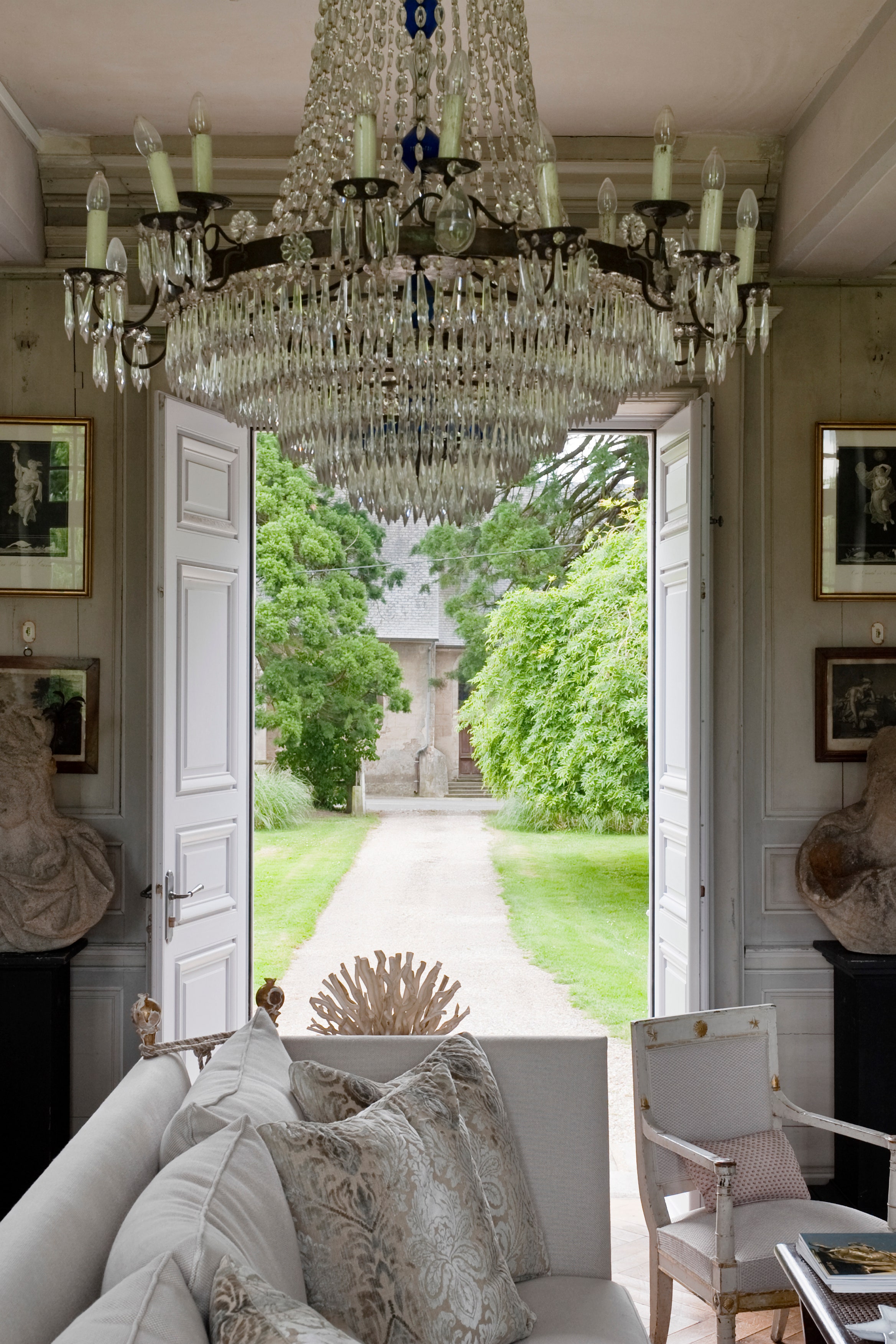 18C chandelier in sitting room furnished with french antiques stone busts and with french doors leading out to the garden