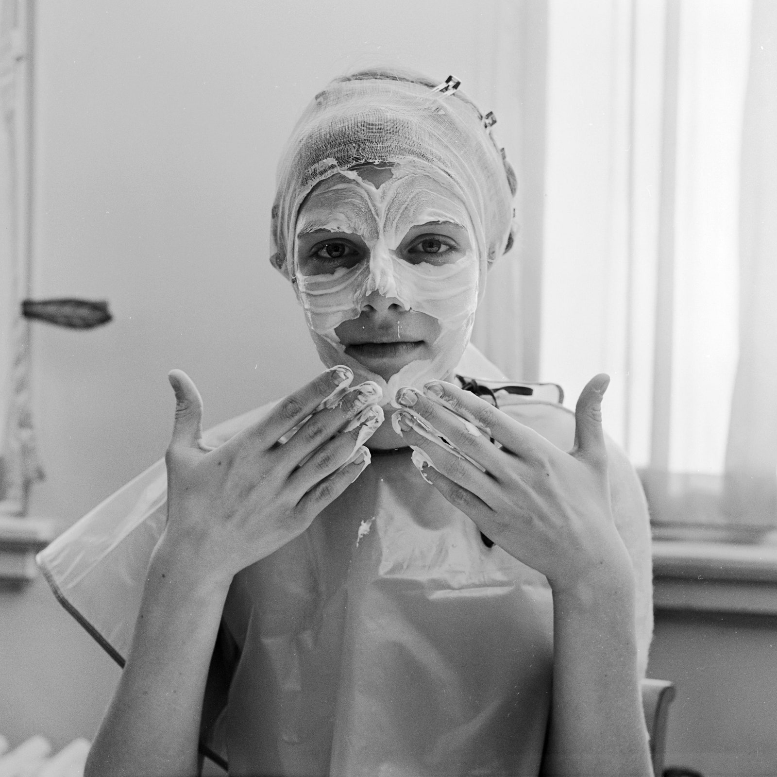 circa 1955  A woman gently applying skin cream to her face with the tips of her fingers.